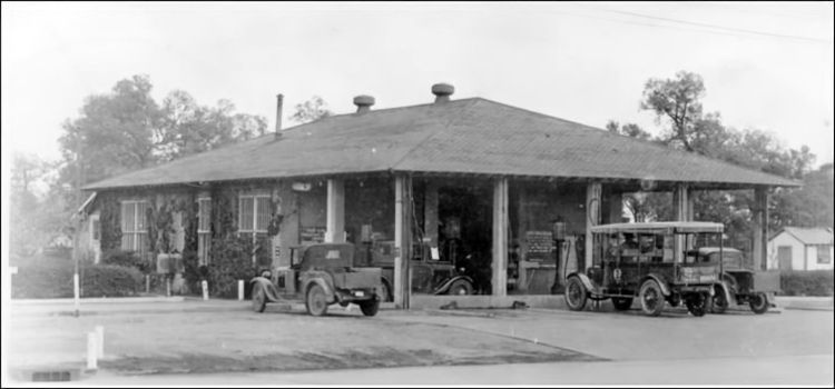 Black and white image of low structure with 1920s cars