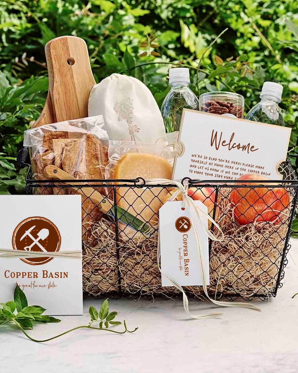A variety of Copper Basin branded items, including a gift tag, welcome card and more, sit in a wire basket.