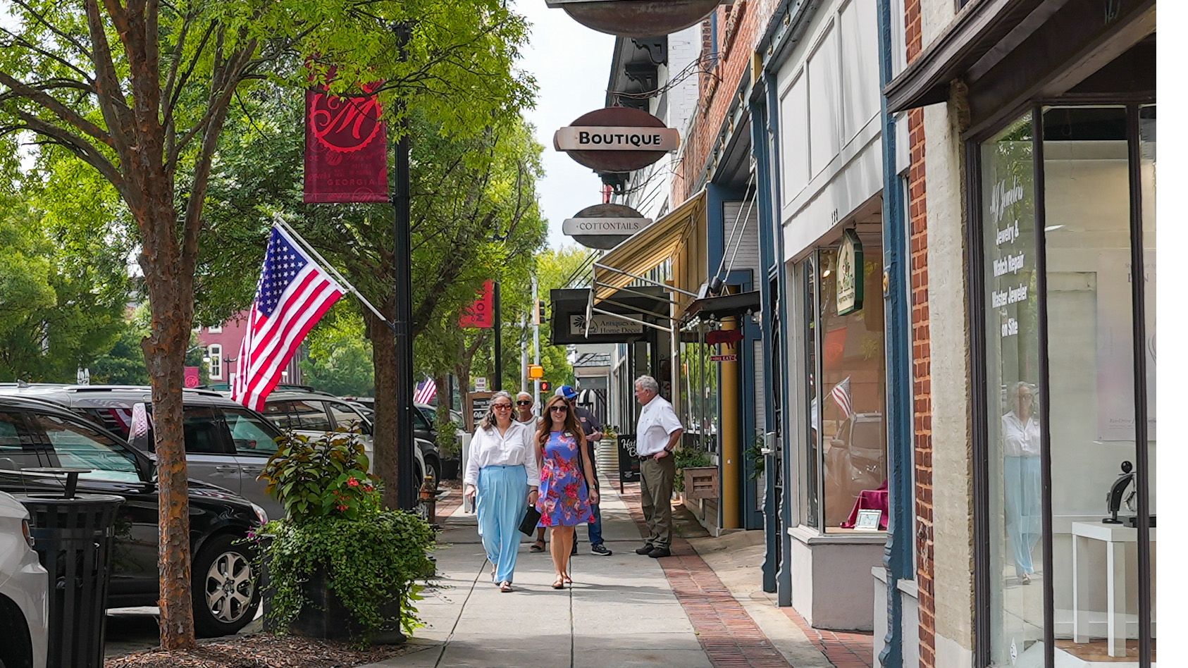 People walk along sidewalks in Monroe, where pole banners spotlight the new community brand.